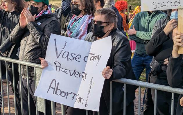 Woman holding sign saying the answer to abortion is vasectomy